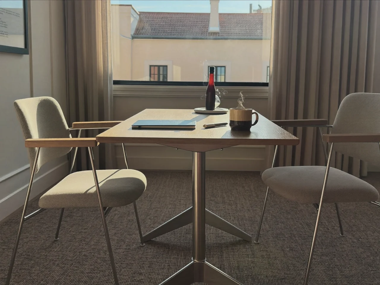 Illustration einer ruhigen Besprechungsecke mit Tisch, Stühlen und Notizbuch