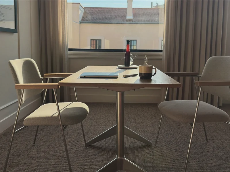 Illustration einer ruhigen Besprechungsecke mit Tisch, Stühlen und Notizbuch